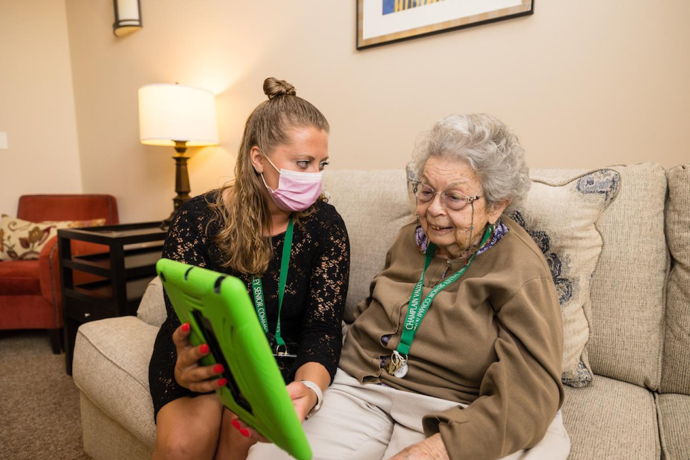 A resident learning how to use a tablet from a family member visiting.