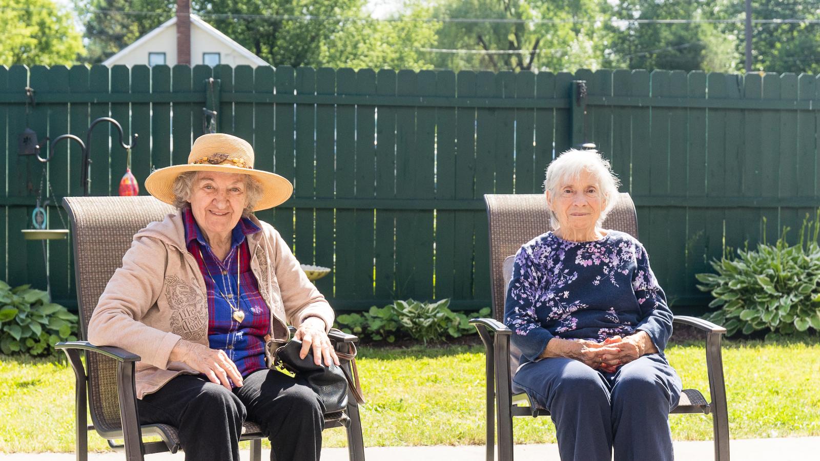 Two residents sitting outside in the sun.