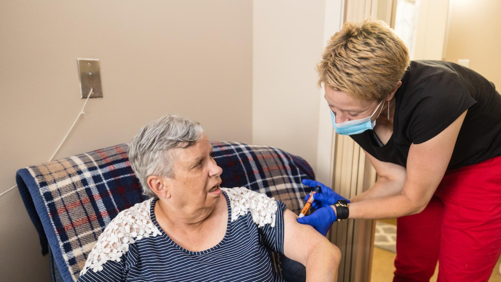 A resident in her Assisted Living room, receiving insulin from a resident nurse.
