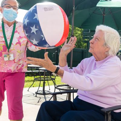 Assisted living resident tossing beach ball to nurse