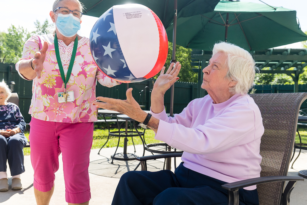 A resident and nurse throwing an inflatable American flag beach ball.