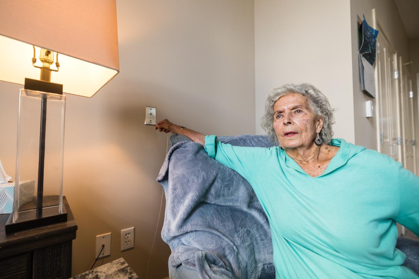 A female resident in a light green shirt using the calling services to alert a nurse.