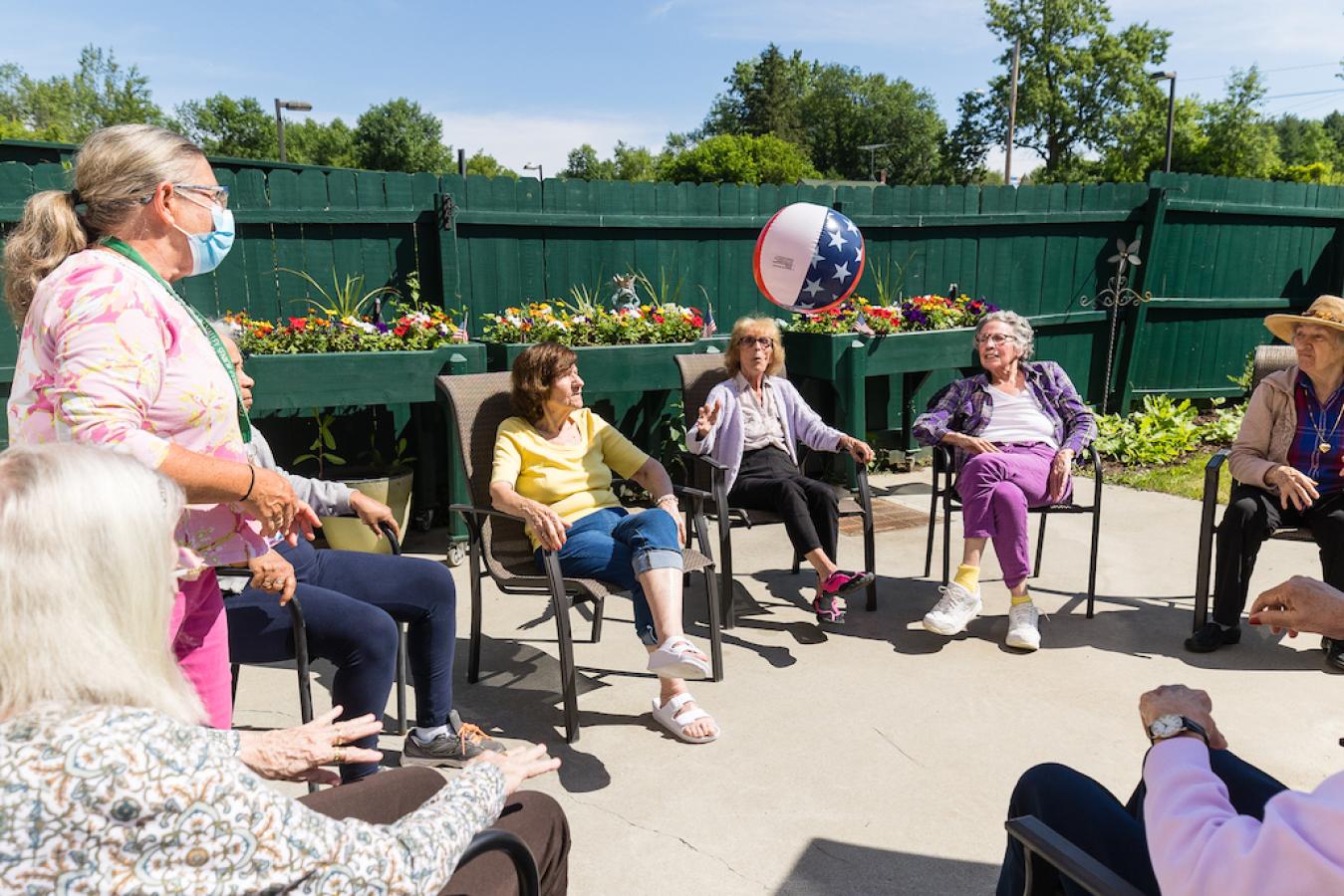 Residents playing with an American flag beach ball outdoors.