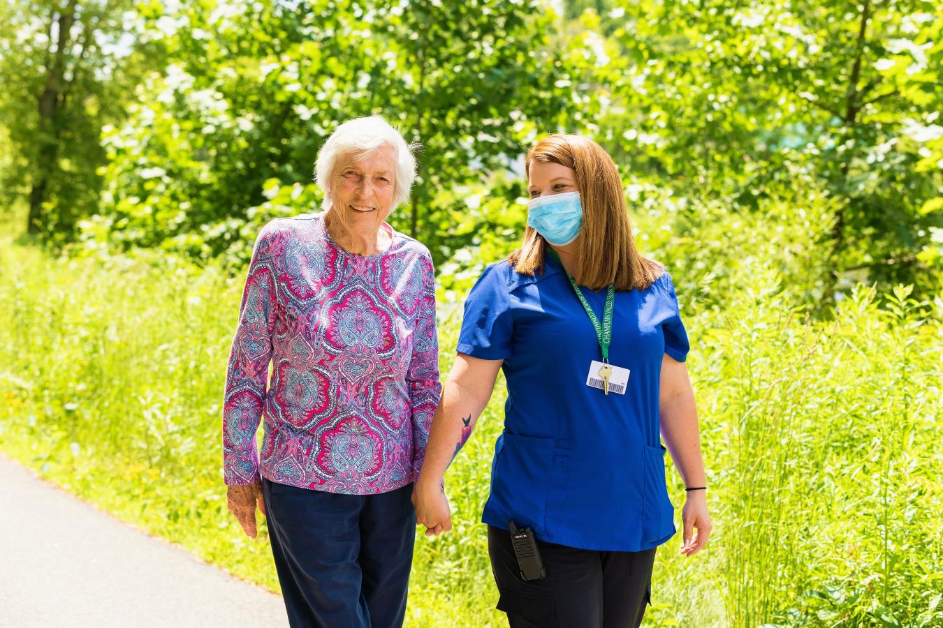 Staff and resident holding hands on a walk. 