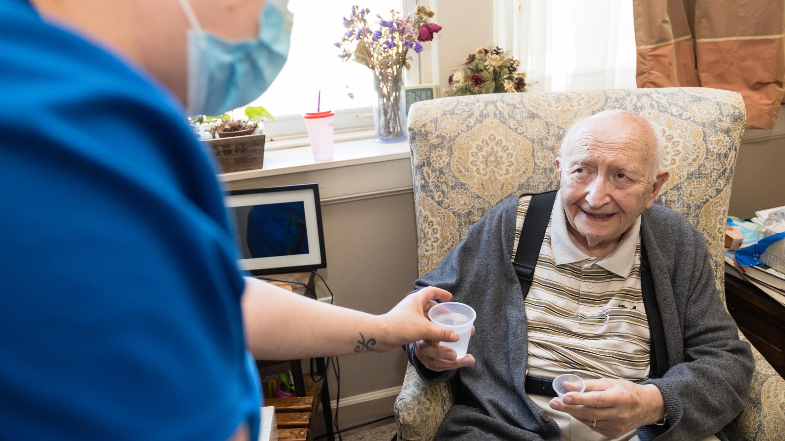 Male resident receiving medication from a staff person. 