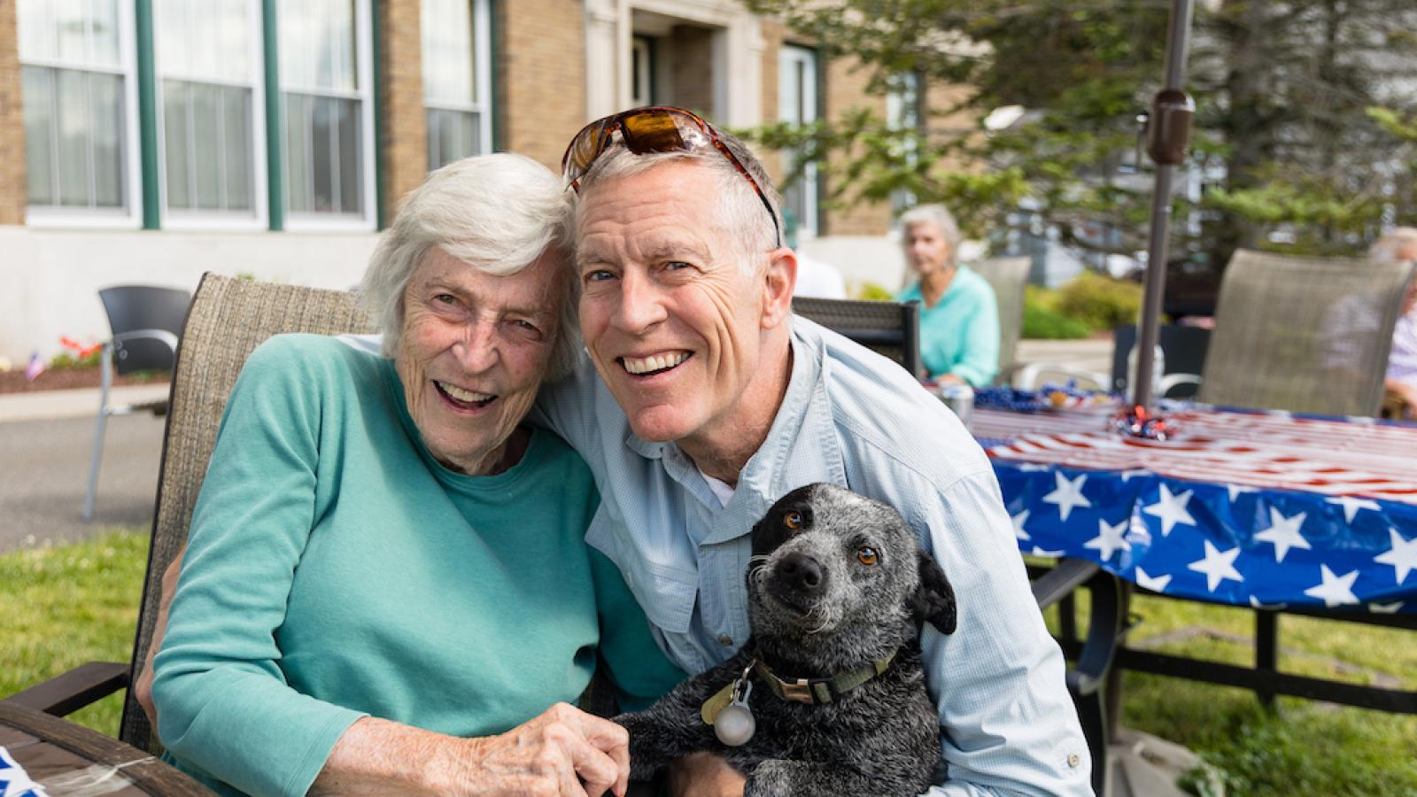 A resident visiting with a family member, holding a medium sized dog.