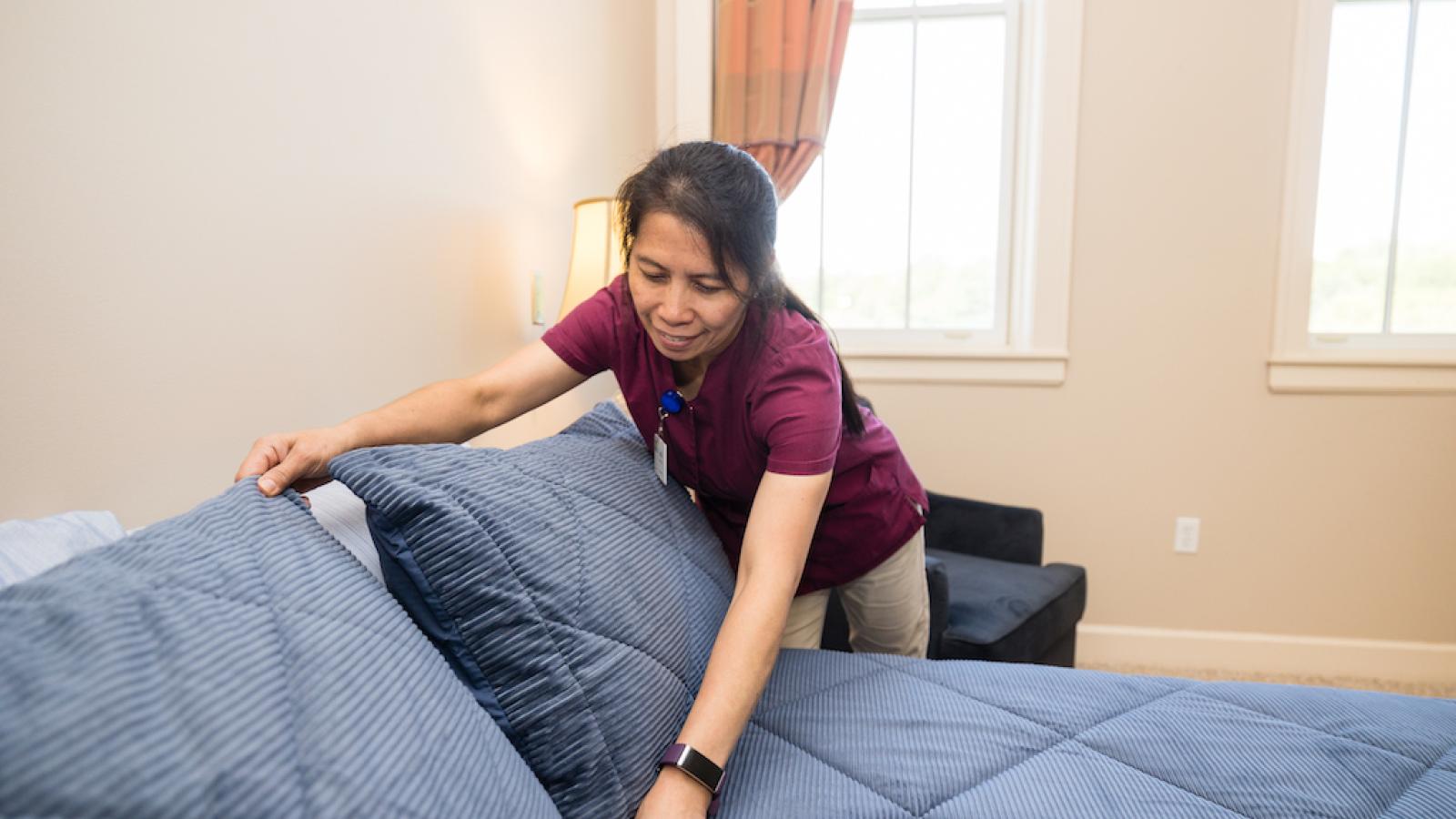 Staff person making a resident's bed.