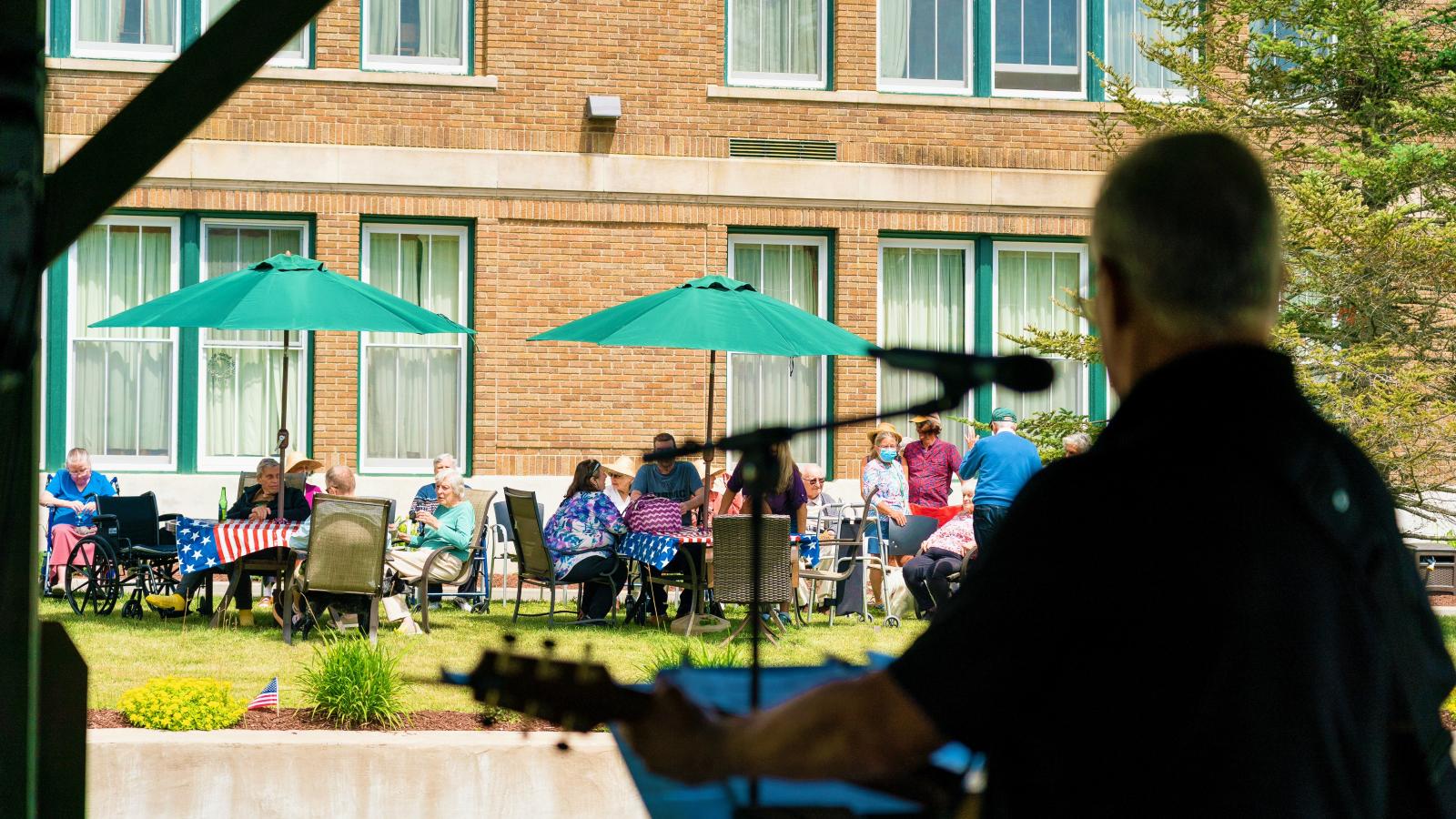 Musician playing outdoors for group of residents. 
