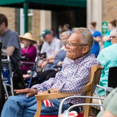 Group of senior assisted living residents listening to musical entertainer. 