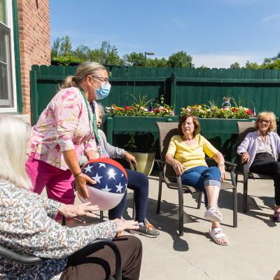 Residents sitting outside enjoying an activity lead by a staff person. 