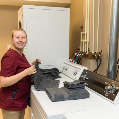 Staff person folding towels in the laundry room. 