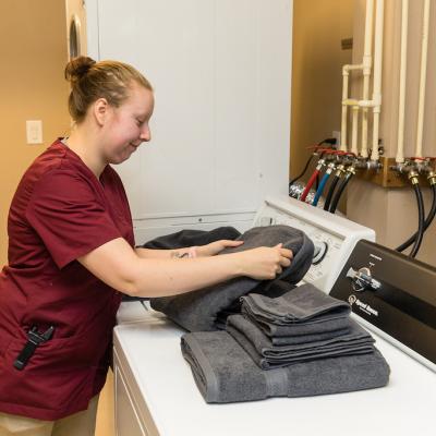 A nurse folding towels for residents, in the laundry room.