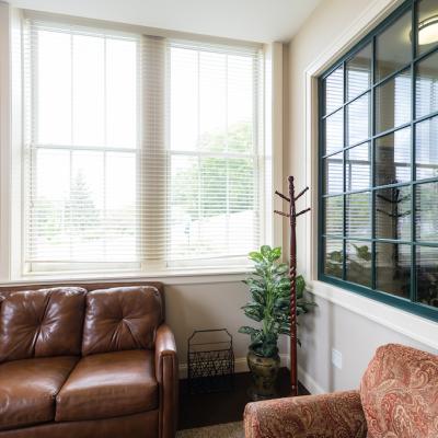 A room with two leather sofas an a coat hanger in the corner.