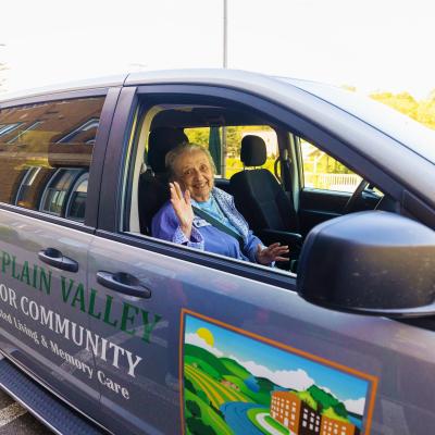 Senior woman waving from front seat