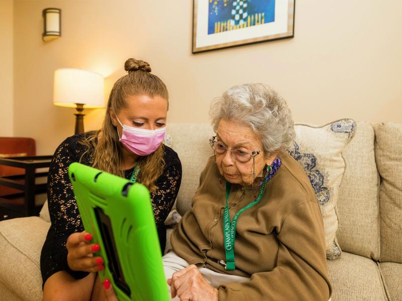 Staff person showing female resident the screen of an Ipad.